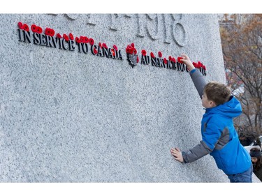 A young boy places his poppy on the cenotaph following Remembrance Day ceremonies at the National War memorial in Ottawa, Friday November 11, 2016.