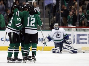 Dallas Stars' Esa Lindell (23), Jamie Oleksiak (5) and Radek Faksa (12) celebrate after Faksa scored against Vancouver Canucks goalie Ryan Miller (30) during the second period of an NHL hockey game, Friday, Nov. 25, 2016, in Dallas.