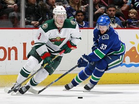 Henrik Sedin checks Charlie Coyle during their NHL game at Rogers Arena February 15, 2016 in Vancouver, British Columbia, Canada.