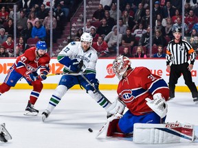 Carey Price makes a stick save while teammate Alexander Radulov defends against Daniel Sedin.