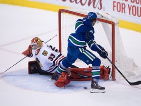 Chicago Blackhawks' goalie Scott Darling, left, loses his glove as he stops Vancouver Canucks' Loui Eriksson, of Sweden, during the overtime period of an NHL hockey game in Vancouver on Nov. 19, 2016.