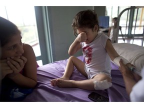 In this Aug. 24, 2016 photo, Ashley Pacheco, 3, cries as she receives an injection as her mother Oriana watches at the University Hospital in Caracas, Venezuela. Two weeks after 3-year-old Ashley scraped her knee, she was screaming in a hospital, fighting for her life as her family scoured Caracas for scarce antibiotics. Venezuela is running short on 85 percent of basic medicines. As the health care system collapses, the tiniest slips, like a little girl's tumble while chasing her brother, are turning into life-or-death crises.