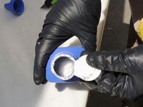A Vancouver RCMP officer opens a printer ink bottle containing the opioid carfentanil imported from China. Drug dealers have been cutting carfentanil and its weaker cousin, fentanyl, into heroin and other illicit drugs to boost profit margins.