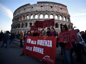Demonstrators hold a banner reading "No violence against women" next to the ancient Colosseum during a rally condemning violence against women in downtown Rome on November 26, 2016.