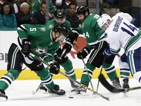 Dallas Stars' Jamie Oleksiak (5), Patrick Sharp (10) and Jordie Benn (24) battle Vancouver Canucks' Alex Burrows (14) for the puck during the first period of an NHL hockey game, Friday, Nov. 25, 2016, in Dallas.