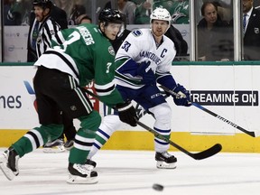 Dallas Stars' John Klingberg (3) and Vancouver Canucks' Henrik Sedin (33) watch after Sedin passes the puck up ice during the second period of an NHL hockey game, Friday, Nov. 25, 2016, in Dallas.