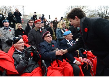 Prime Minister Justin Trudeau talks to veterans during a Remembrance Day ceremony at the National War Memorial in Ottawa on Friday, Nov. 11, 2016.
