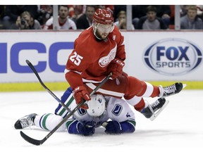 Defenceman Mike Green of the Detroit Red Wings sits on Canucks' defenseman Luca Sbisa during an NHL game on Thursday in Detroit. After blowing a quick start to the NHL marathon season, the Canucks are now looking up at the pacesetters.