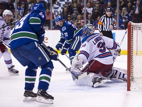 Henrik Lundqvist of the Rangers slides across his crease after Daniel Sedin passed the puck to brother Henrik.
