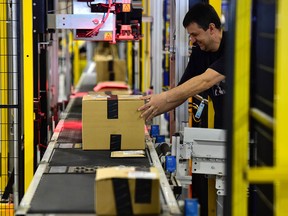 An employee packages customers' orders before dispatching them at the Amazon electronic commerce company's logistics center in San Fernando de Henares, near Madrid, on the eve of "Black Friday", on November 24, 2016.