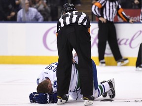 Referee Kelly Sutherland (11) checks on Vancouver Canucks left wing Daniel Sedin (22) who was hit by Toronto Maple Leafs centre Nazem Kadri  after scoring during third period NHL hockey action in Toronto on Saturday, November 5, 2016.