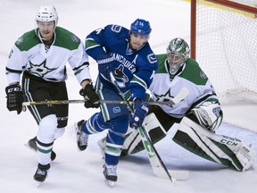 Dallas Stars defenceman Jamie Oleksiak tries to clear Canucks right wing Alexandre Burrows from in front of the Stars net.
