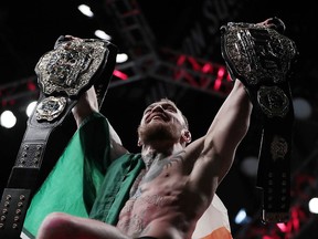 Conor McGregor holds up his title belts after he defeated Eddie Alvarez during a lightweight title mixed martial arts bout at UFC 205, early Sunday, Nov. 13, 2016, at Madison Square Garden in New York.