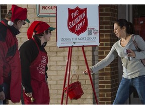 A woman(R) makes a donation into a Salvation Army kettle outside a Giant grocery store November 24, 2012, in Clifton, Virgina, as bell ringers William Schmidt (L) and his grandson Bubba Wellens(C) thank a woman making the donation. Salvation Army volunteers traditionally are seen collecting donations from holiday shopper for the needy between Thanksgiving and Christmas. Schmidt does it all "to teach others the joy of giving".