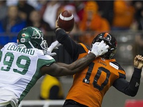 The Lions' Jonathan Jennings gets a pass away despite pressure from the Roughriders' A.C. Leonard.