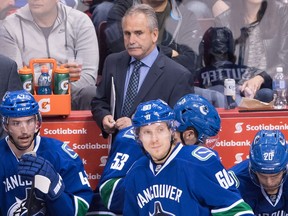 Vancouver Canucks' head coach Willie Desjardins, top, stands on the bench behind Sven Baertschi, Markus Granlund, Bo Horvat and Brandon Sutter during the third period of an NHL hockey game against the New York Rangers in Vancouver.