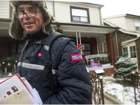 A Canada Post employee delivers mail and parcels to residential homes in Toronto. A new report wants home delivery restored to the level it was before the 2015 federal election campaign.