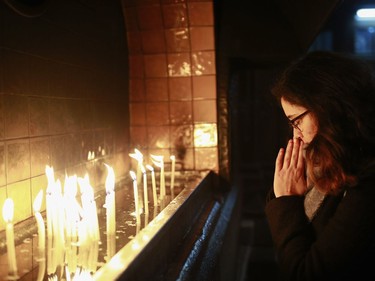 A woman prays after lighting a candle prior to a Christmas Eve mass in Sent Antuan church, the largest church of the Roman Catholic Church in Istanbul, Saturday, Dec, 24, 2016.