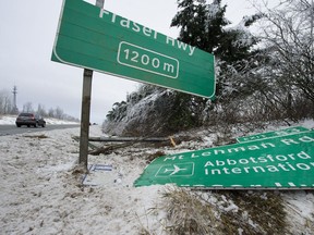 Motorists drive past a damaged highway sign alongside Highway 1 in Abbotsford on Sunday. Rain fell in the western Fraser Valley on Sunday but more snow was forecast.
