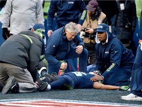 Head coach Pete Carroll of the Seattle Seahawks tends to wide receiver Tyler Lockett #16 after he was injured in a play against the Arizona Cardinals at CenturyLink Field on December 24, 2016 in Seattle, Washington.