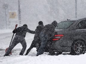 People push a car during an Environment Canada snow fall warning at Simon Fraser University in Burnaby, BC., December 5, 2016.