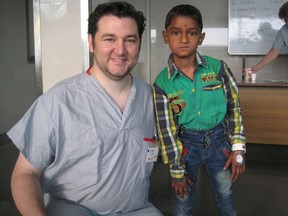 Burnaby plastic surgeon Colin White with the six-year-old Indian boy he successfully operated on. The boy had fallen into a fire, causing his arm to be fused to his chest from the burn.