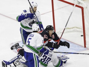 Carolina Hurricanes' Jeff Skinner (53) scores and dives over Vancouver Canucks goalie Ryan Miller (30) as Canucks' Luca Sbisa (5), of Italy, and Erik Gudbranson defend during third period of an NHL hockey game in Raleigh, N.C., Tuesday, Dec. 13, 2016. Carolina won 8-6.