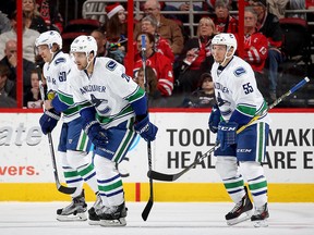 Brandon Sutter skates back to the bench with teammates Markus Granlund and Alex Biega after scoring.