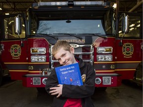Nathan McTaggart poses in Coquitlam with the book he wrote about Santa getting stuck in the chimney and firefighters having to rescue him.