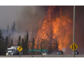 Heat waves are seen as cars and trucks try and get past a wild fire 16km south of Fort McMurray on highway 63 Friday, May 6, 2016. The ferocious wildfire that forced nearly 90,000 to flee Canada's oilsands region and reduced thousands of homes to rubble has been picked as the top news story of 2016 in an annual survey of newsrooms across Canada by The Canadian Press.