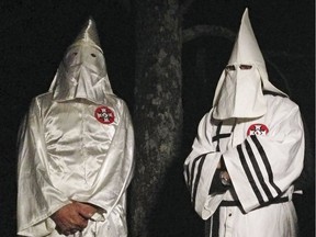 In this Friday, Dec. 2, 2016 photo, two masked Ku Klux Klansmen stand on a muddy dirt road during an interview near Pelham, N.C. The KKK and other white extremist groups don't like being called "white supremacists," a phrase that dates to the earliest days of white racist movements in the United States.
