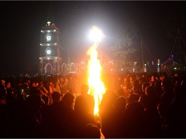 Indian Christian devotees stand beside a bonfire marking Christmas Eve outside St. Peter's Church in Allahabad on December 24, 2016.