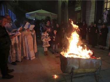 Iraqi Christians gather around a fire during Christmas Eve mass at a church in Basra, 340 miles (550 kilometers) southeast of Baghdad, Iraq, Saturday, Dec. 24, 2016.