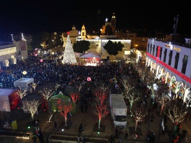 People take part in the Christmas Eve celebrations on December 24, 2016 at the Manger Square next to the Church of the Nativity, revered as the site of Jesus Christ's birth, in the biblical West Bank town of Bethlehem. Crowds gathered in Bethlehem for Christmas Eve celebrations ahead of midnight mass at the spot where Christians believe Jesus was born, with more visitors expected than in 2015 due to a drop in violence.