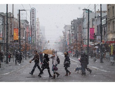 Pedestrians cross Granville St. as snow falls in downtown Vancouver, B.C., on Monday December 5, 2016. Environment Canada has issued a snowfall warning for Metro Vancouver.