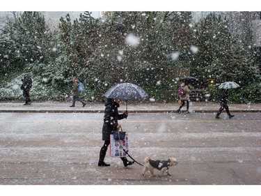 Pedestrians walk along Robson St. as snow falls in downtown Vancouver, B.C., on Monday December 5, 2016. Environment Canada has issued a snowfall warning for Metro Vancouver.