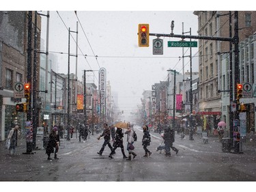 Pedestrians cross Granville St. as snow falls in downtown Vancouver, B.C., on Monday December 5, 2016. Environment Canada has issued a snowfall warning for Metro Vancouver.