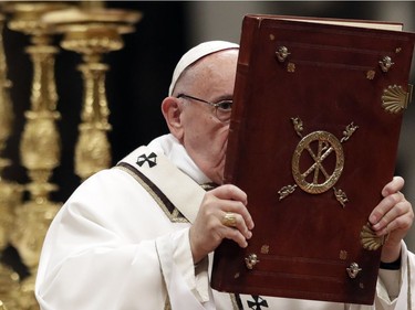 Pope Francis hoists the book of the Gospels as he celebrates the Christmas Eve Mass in St. Peter's Basilica at the Vatican, Saturday, Dec. 24, 2016.
