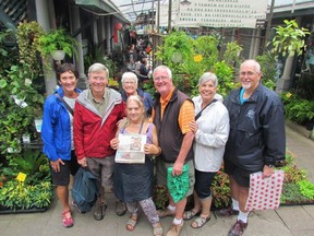 Travellers from B.C. — from left, Carol Davis, David Sykes, Patricia Ross, Joe Vanderkooy, Lynne Vanderkooy and Bob Ross — found the woman (centre front) whose photo was featured in a Vancouver Sun travel story a year earlier, in the Bolhao market in Porto, Portugal, this fall. They never did get her name, but here holding the travel section front page with her photo on it she is wearing the same top she wore in the 2015 Vancouver Sun photo.