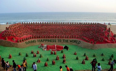 People walk past a sculpture by Indian sand artist Sudarsan Pattnaik featuring around 1000 Santa Claus figures at Puri Beach, some 65km east of Bhubaneswar, on December 24, 2016. Although Indian Christians make up just two percent of the country's billion plus population, Christmas has become a popular festival in the Indian calendar.