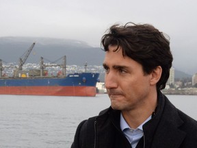 A freighter is seen in the background as Prime Minister Justin Trudeau tours Vancouver harbour in December.