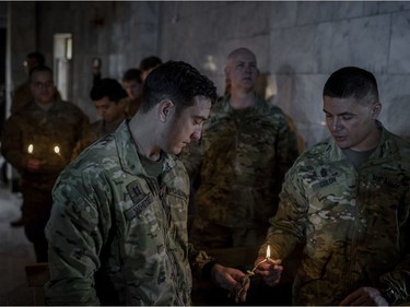 U.S. Army personal light candles dring Christmas Eve's Mass in the Assyrian Orthodox church of Mart Shmoni, in Bartella, Iraq, Saturday, December 24, 2016. For the 300 Christians who braved rain and wind to attend the mass in their hometown, the ceremony provided them with as much holiday cheer as grim reminders of the war still raging on around their northern Iraqi town and the distant prospect of moving back home. Displaced when the Islamic State seized their town in 2014, they were bused into the town from Irbil, capital of the self-ruled Kurdish region, where they have lived for more than two years.
