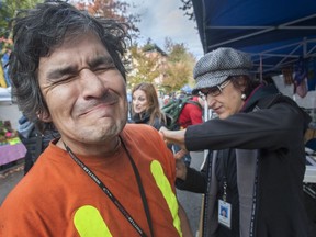 Mitchell Lagimodiere grimaces as Elena gives him a flu shot at Pigeon Park in Vancouver.