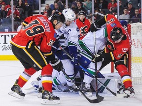 Alex Chiasson #39 (L) and Sam Bennett #93 of the Calgary Flames look fight for the puck in front of the net against Henrik Sedin #33 of the Vancouver Canucks during an NHL game at Scotiabank Saddledome on December 23, 2016 in Calgary, Alberta, Canada.