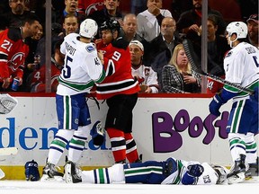 Taylor Hall #9 of the New Jersey Devils and Michael Chaput of the Vancouver Canucks come together after Taylor Hall checks Philip Larsen #63 to the ice during the game at Prudential Center on December 6, 2016 in Newark, New Jersey.