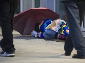 A person sleeps on the sidewalk in the 100-block of East Hastings after sunset on Wednesday.