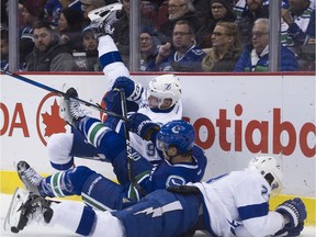 Vancouver Canucks #5 Luca Sbisa and Tampa Bay Lightning #92 Joel Vermin crash to the ice alongside Tampa Bay Lightning #23 J.T. Brown in the second period of a regular season NHL hockey game at Rogers Arena, Vancouver, December 16 2016.