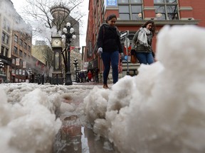 Pedestrians cross a snow-covered street in Vancouver, Monday, Dec.19, 2016. An early morning snowfall paralyzed the commute around Greater Vancouver on Monday.