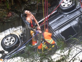 Pender Harbour volunteer firefighter Bill Gilkes holds Carolynne Drane's hands while Sechelt firefighter Tyrel Brackett fits her with a harness during a harrowing rescue on Nov. 23.