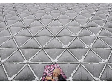 A woman uses her iPhone to photograph snow falling outside the Bloedel Conservatory at Queen Elizabeth Park in Vancouver, B.C., on Monday December 5, 2016. Environment Canada has issued a snowfall warning for Metro Vancouver.